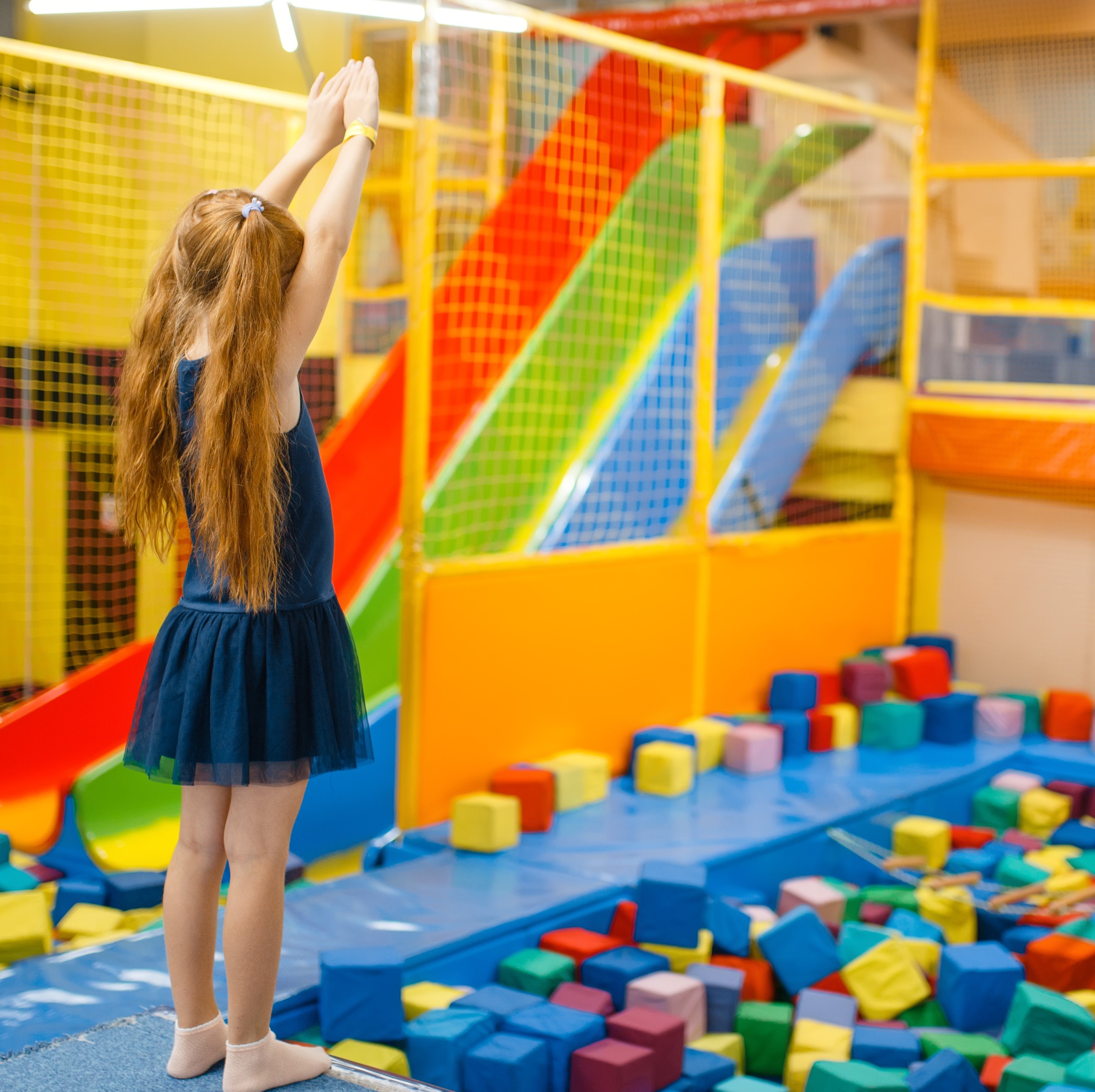 Adorable girl jumping on kids trampoline, playground in entertainment center. Play area indoors, playroom